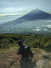 Rear view of man looking at mountains against sky