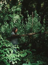 Full length of woman holding plant in forest