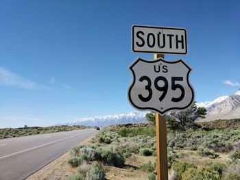 Road sign on landscape against blue sky