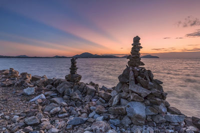Rocks on beach against sky during sunset