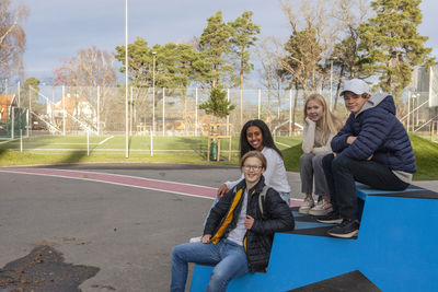 Portrait of teenage friends sitting in schoolyard