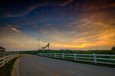 Road by street against sky during sunset