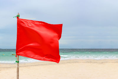 Red umbrella on beach against sky