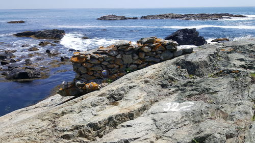 Rocks on sea shore against sky