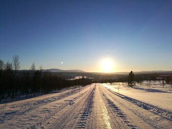 Snow covered railroad tracks against sky during winter