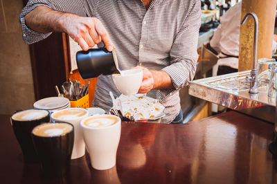 Midsection of man making froth art in coffee cup