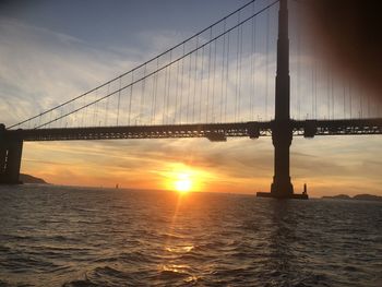 View of suspension bridge over sea during sunset