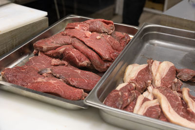 Large steaks of raw beef arranged on a steel pan before cooking.