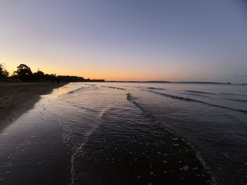 Scenic view of beach against clear sky during sunset