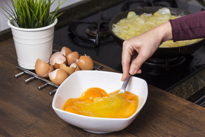 Cropped hands of woman mixing eggs in bowl on table