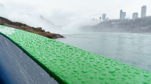 Close-up of river by cityscape against sky