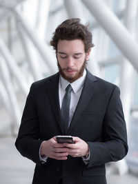 Businessman using mobile phone while standing in building