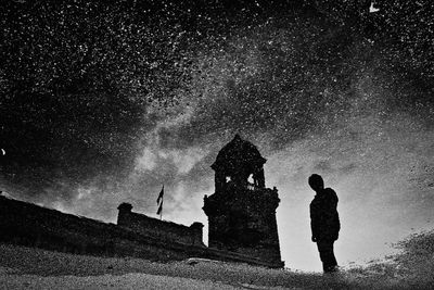 Low angle view of man standing against sky at night