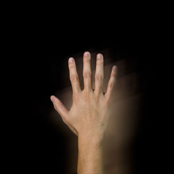 An asian hand raised on black background showing the back of his hand