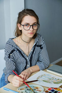 Millennial girl draws fabulous images on paper while sitting at home