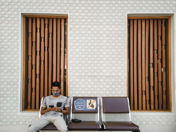 Rear view of man sitting on wall