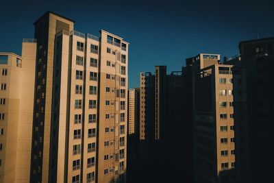 Buildings in city against clear blue sky