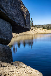 Rock formation in lake against clear blue sky