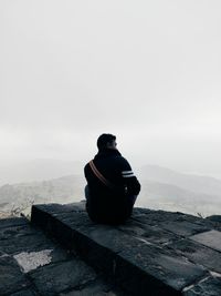 Rear view of man sitting on mountain road