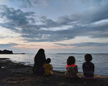 Rear view of people sitting at beach