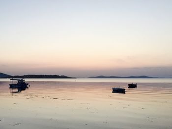 Boats in sea at sunset