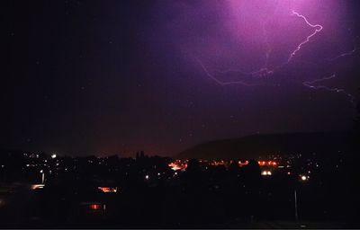 Illuminated cityscape against sky at night