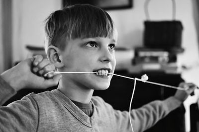 Close-up of boy biting thread