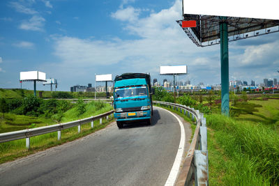 Cars on road against sky in city