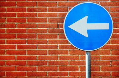 Close-up of road sign against brick wall