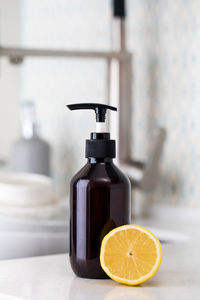 Bottle with eco friendly dishwashing detergent with lemon on the background of a sink 