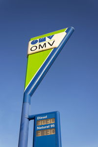 Low angle view of road sign against clear blue sky