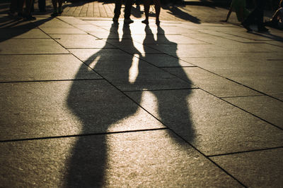 Shadow of people walking on footpath during sunset