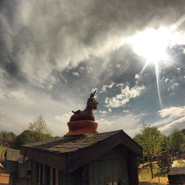 building exterior, built structure, architecture, sky, low angle view, sunbeam, sun, sunlight, cloud - sky, religion, tree, spirituality, lens flare, place of worship, house, statue, sculpture, outdoors, cloud