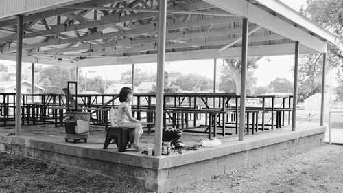 Rear view of woman sitting on bridge