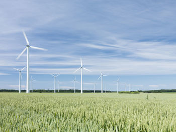 Wind turbines on field against sky