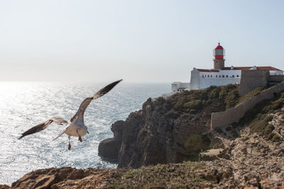 View of lighthouse by sea against sky