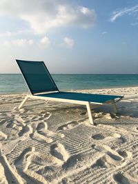Chair on beach against sky