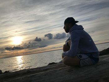 Man looking at sea against sky during sunset