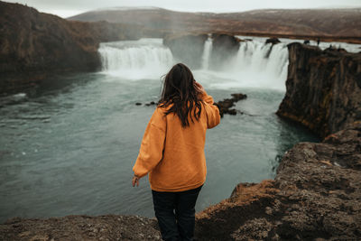 Back view woman between wild lands with waterfall