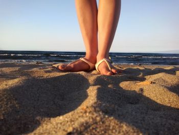 Low section of woman standing on beach
