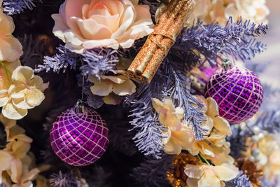 Close up of christmas tree decorated with artificial cinnamon sticks and purple balls . new year 