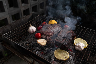 Garlic,tomatoes and meat on the grill on hot coals with smoke.