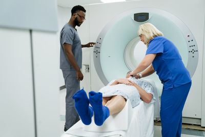 Doctor looking at nurse preparing for mri scan on patient in examination room