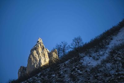 Low angle view of snowcapped mountain against clear blue sky