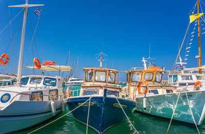 Sailboats moored at harbor against clear blue sky