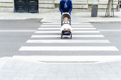 Man walking with baby stroller while crossing road in city