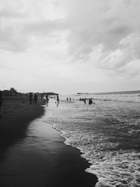 People enjoying at beach against sky