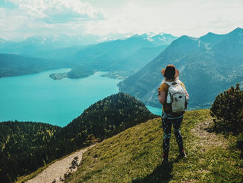 Rear view of man standing on mountain against sky