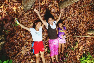 High angle view of siblings lying on ground in forest