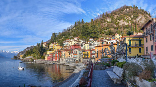 Houses by lake against sky in city